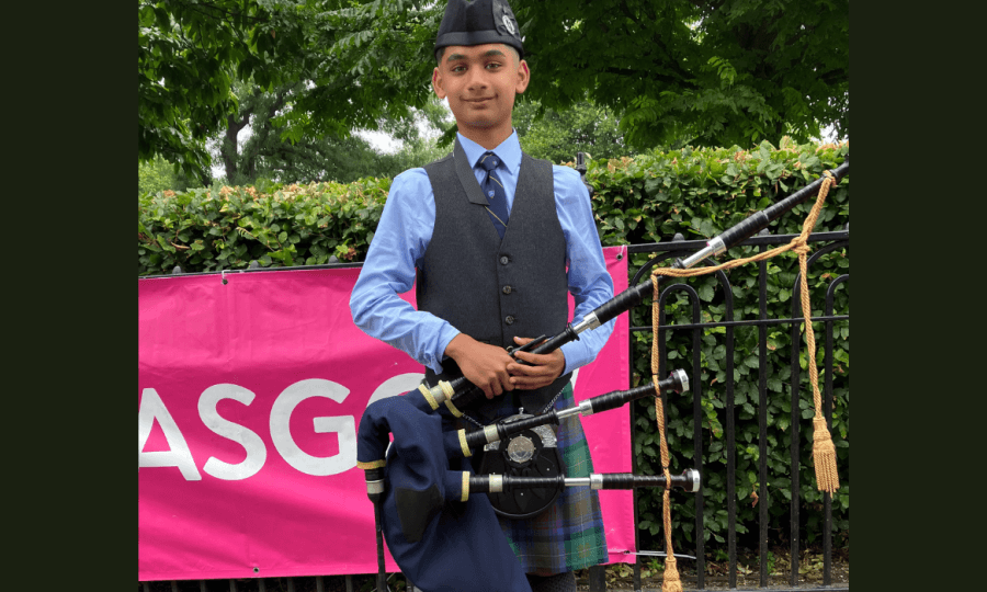 Keshav standing width bagpipes in a kilt.